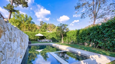 High hedges surround a pool with a stone back wall Photo