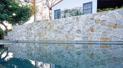 A reflection of a stone wall and white house in pool water Photo