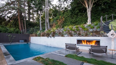 Sunny suburban getaway: rectangular pool in a backyard oasis filled with lush greenery Photo