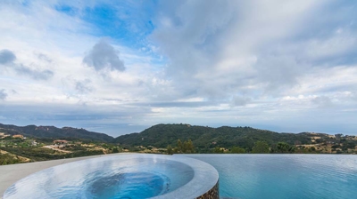 Tranquil oasis: infinity pool and hot tub surrounded by picturesque mountain scenery." Photo