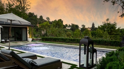 Lush greenery surrounds a rectangular pool and jacuzzi Photo