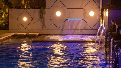 Pool with light on the wall outside at night time Photo