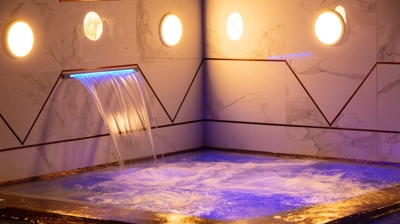 Built in waterfall into the pool with lights above it Photo