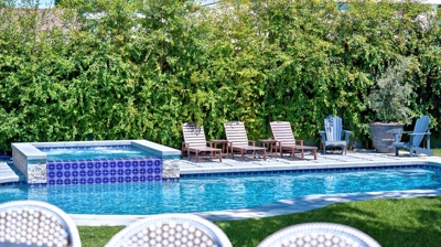 Outdoor dining table with pool and jacuzzi in the background Photo