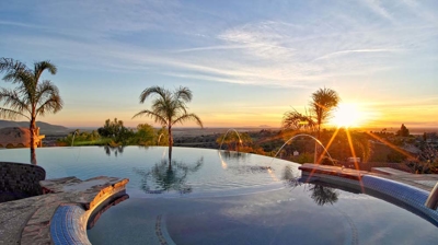 An eternal pool framed by towering palm trees neighboring a pristine putting green. Photo