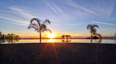 A timeless infinity pool embraced by tropical palms beside a meticulously kept putting green. Photo