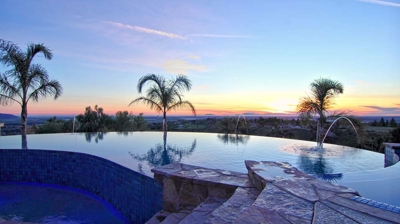 A timeless pool bordered by towering palm trees alongside a manicured putting green. Photo