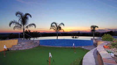 An endless expanse of water enclosed by elegant palm trees by a well-kept putting green. Photo