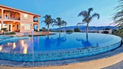 A residence and pool framed by slender palm trees. Photo