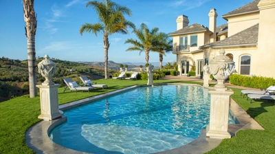 A majestic pool encircled by verdant lawns and sculpted figures atop columns. Photo