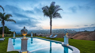 An opulent pool ensconced in grass and accentuated by statues perched on pillars. Photo
