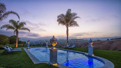 A lavish aquatic sanctuary embraced by verdant lawns and adorned with statues mounted on pillars. Photo