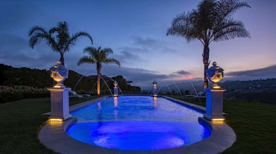 An aquatic retreat ensconced in greenery and enhanced by statues positioned on pillars. Photo