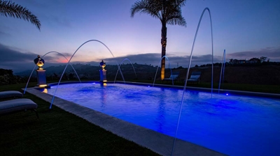 A pool oasis embraced by manicured grass and graced with statues on pillars. Photo