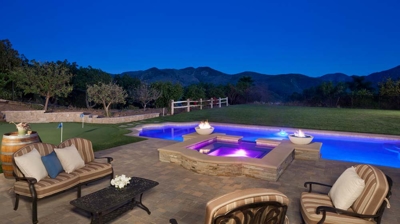 Custom patio seating area, pool, and spa with mountain view at night Photo