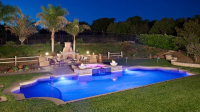 Illuminated pool and backyard patio area at night Photo