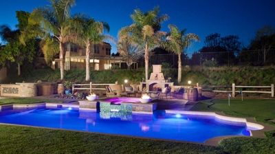 View over pool and patio area with custom fireplace and spa Photo