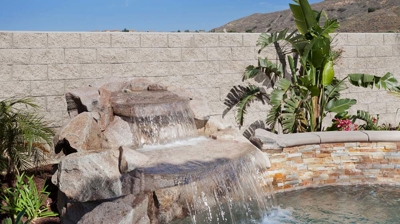 Pool retreat with palm tree and spa showcasing a mesmerizing waterfall. Photo