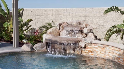 Desert oasis pool with palm tree and spa accompanied by a soothing waterfall. Photo
