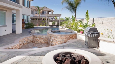 Desert oasis featuring a pool with palm tree and spa with a soothing waterfall. Photo