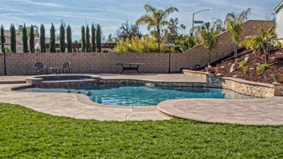 Open-air meandering pool with a spa and verdant lawn. Photo