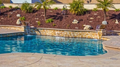 Exterior curvaceous pool featuring a spa and lush greenery. Photo