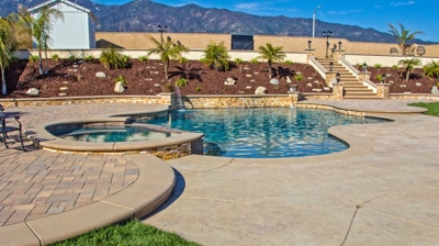 Outdoor sinuous pool flanked by a spa and verdant landscape. Photo