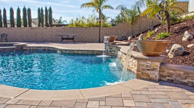 Curving pool nestled amidst greenery with a spa. Photo