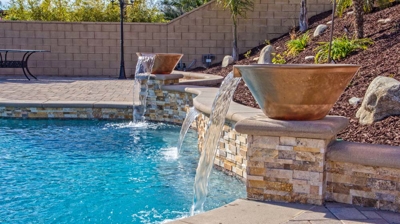 Exterior pool with waterfall pots accompanied by a spa and vibrant grass. Photo