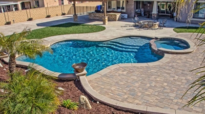 Exterior curvilinear pool bordered by a spa and foliage. Photo