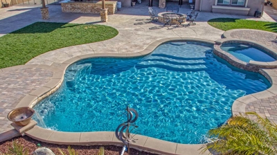 Open-air winding pool featuring a spa and verdant surroundings. Photo