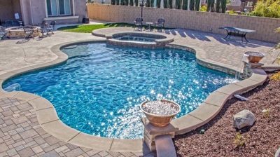 Outdoor pool with a spa and landscaping. Photo