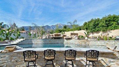 A poolside bar area with seating for guests overlooking a pool. Photo