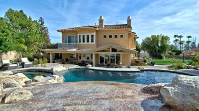 Arid haven boasting a pool and spa, surrounded by desert rocks and palm fronds. Photo