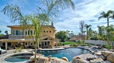 Arid retreat featuring a pool and spa nestled amidst rocks and palm trees. Photo