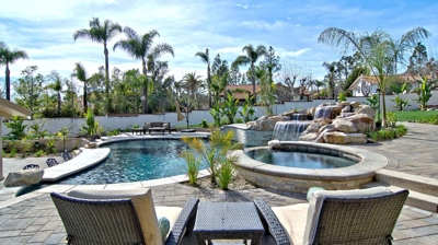 Desert sanctuary with a pool and spa enveloped by rocky terrain and palm foliage. Photo