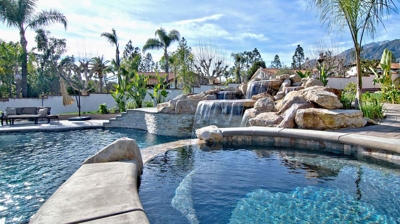 Desert paradise with a pool and spa, set amidst rocky outcrops and towering palms. Photo