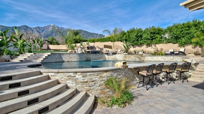 Desert retreat showcasing a pool and spa, encircled by natural rock formations and palm groves. Photo
