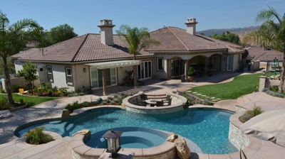 Garden paradise with a pool, spa, and incorporated fire pit in a verdant setting. Photo