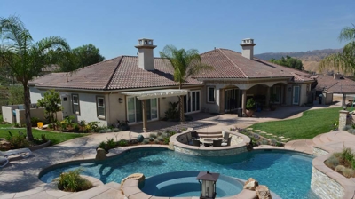 Backyard sanctuary surrounded by lush greenery, with a pool, spa, and built-in fire pit. Photo