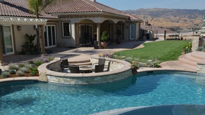 Tropical oasis featuring a pool, spa, and sunken fire pit in the lush backyard. Photo