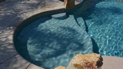 Tropical oasis with a pool, spa, and integrated fire pit in the lush backyard. Photo