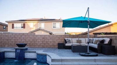 Backyard boasting a blue-tiled pool, spa, and captivating fire elements. Photo