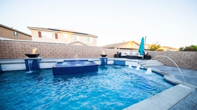 A backyard boasting a generously sized pool, accented by vivid blue tiles, accompanied by a rejuvenating spa. Photo
