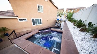 Poolside sanctuary featuring sunken pool, elevated spa, and serene waterfall. Photo