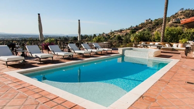 Architectural marvel: a Spanish-style home with a sumptuous pool featuring cascading water elements. Photo