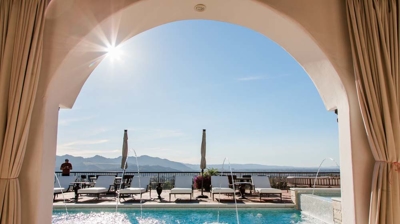 Architecturally stunning Spanish home featuring a luxurious pool area with white arches. Photo