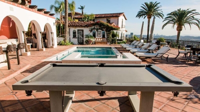 Outdoor pool table next to a Spanish style residence. Photo