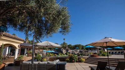 A lounge area shaded by umbrellas and trees. Photo