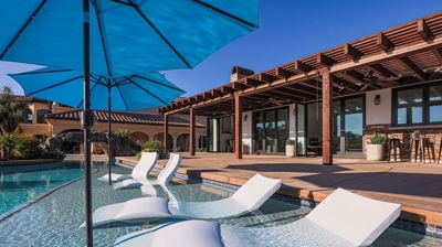 Luxurious pool oasis with submerged lounge chairs under umbrella shades. Photo